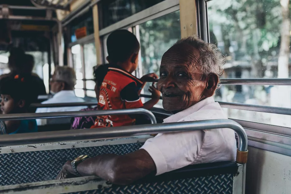 Senior man sitting on the bus, looking at the camera.