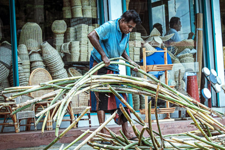 Image of man processing bamboo for weaving