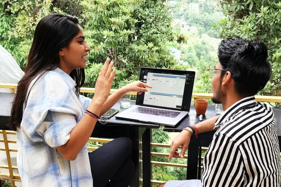 Young South Asian woman and man talking in front of an open laptop