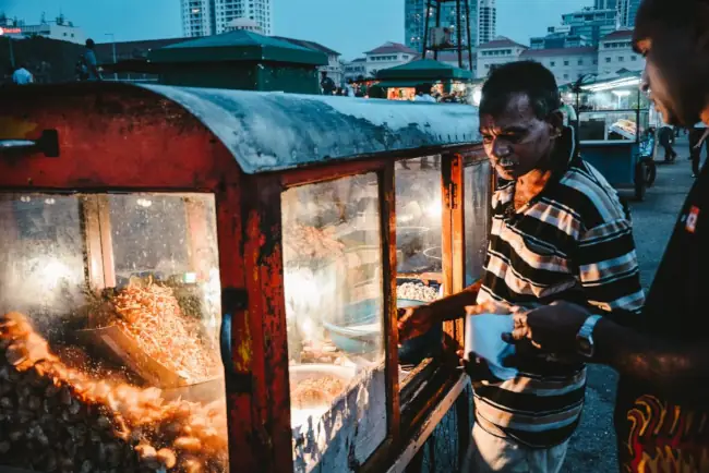 Man selling snack food from cart at night in Sri Lanka